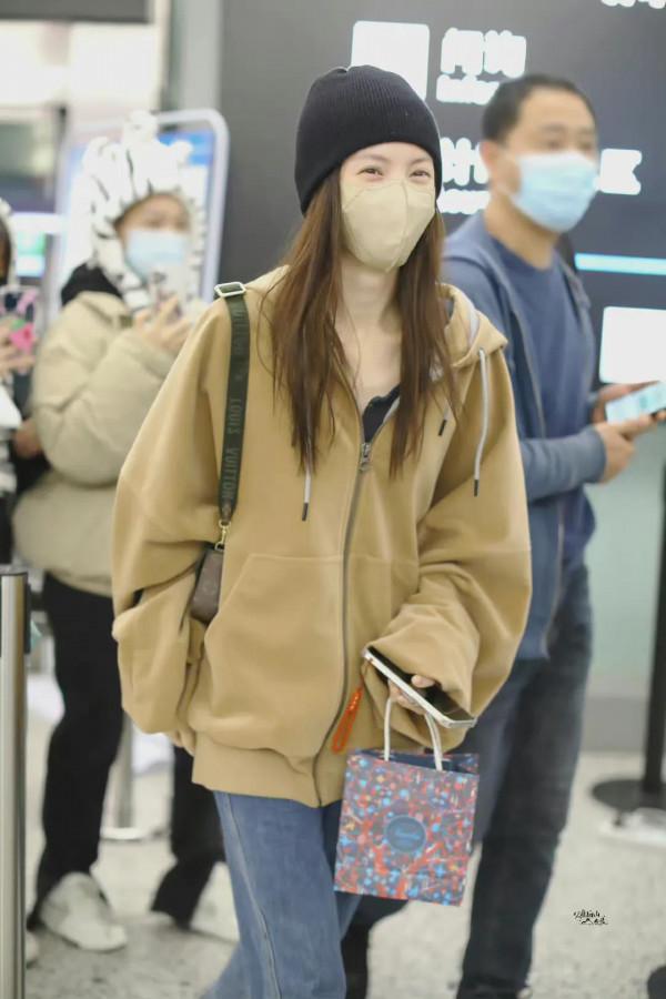 金晨機場私服，棕連帽外套搭配後開衩毛邊牛仔褲，眼睛散發著笑容