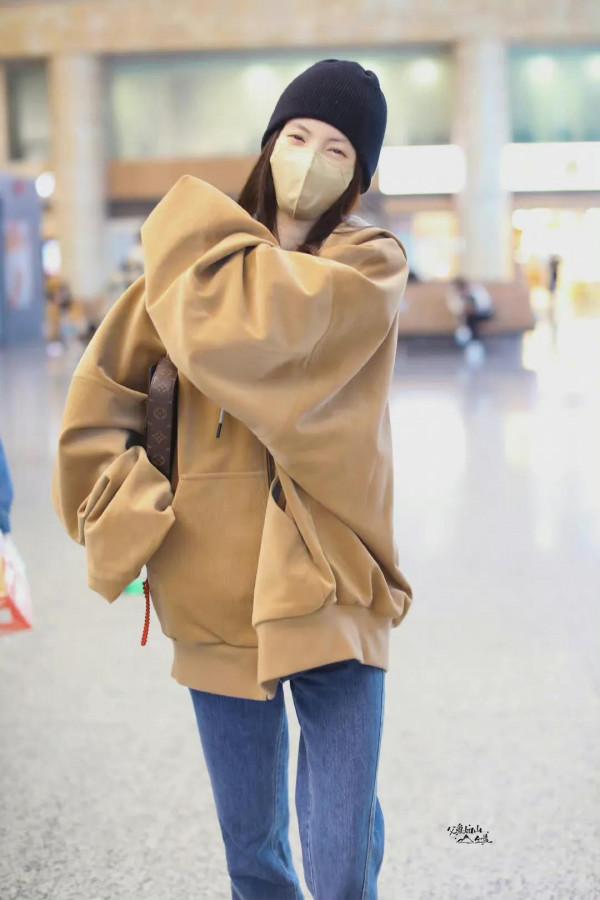 金晨機場私服，棕連帽外套搭配後開衩毛邊牛仔褲，眼睛散發著笑容