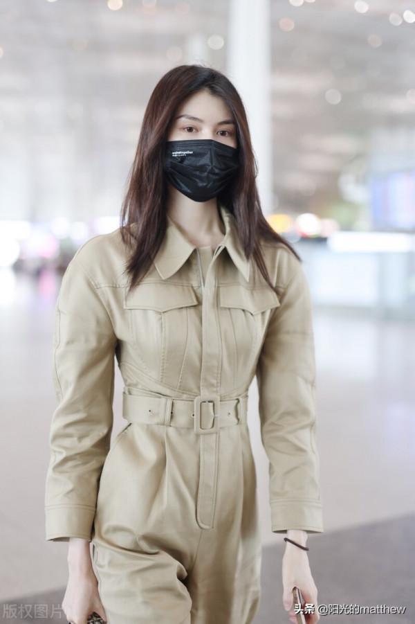 何穗身穿米色工裝連體服腰細腿長，長髮垂肩清新優雅