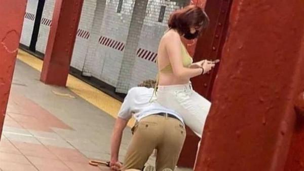 男子跪地鐵月臺旁邊,女子坐他背上玩手機 男子跪地鐵月臺旁邊,女子坐他背上玩手機