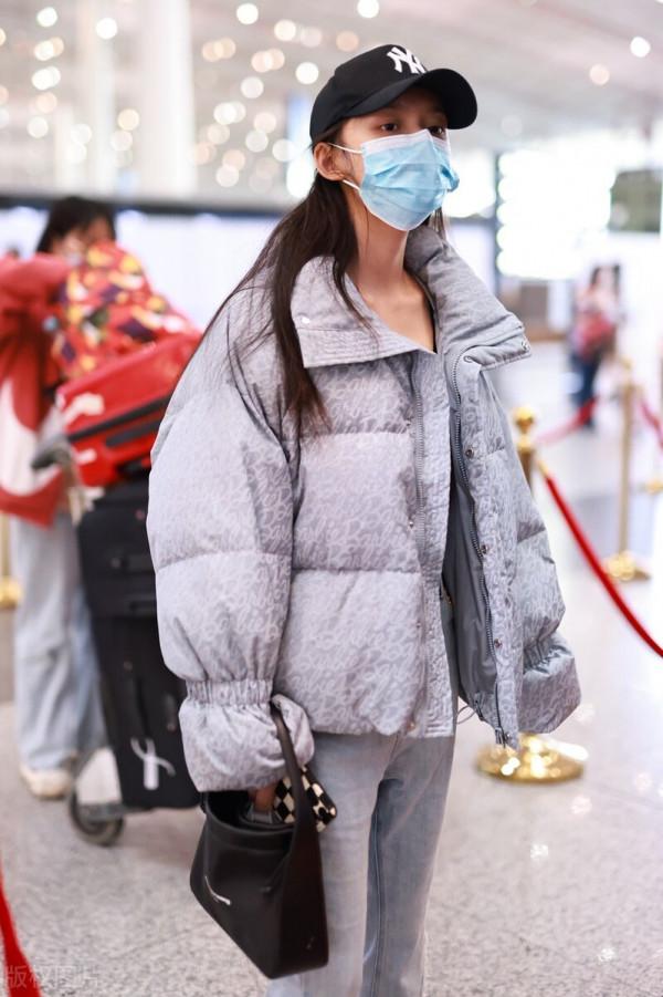 林允穿灰色羽絨服搭配牛仔開衩褲，戴棒球帽溫暖時尚