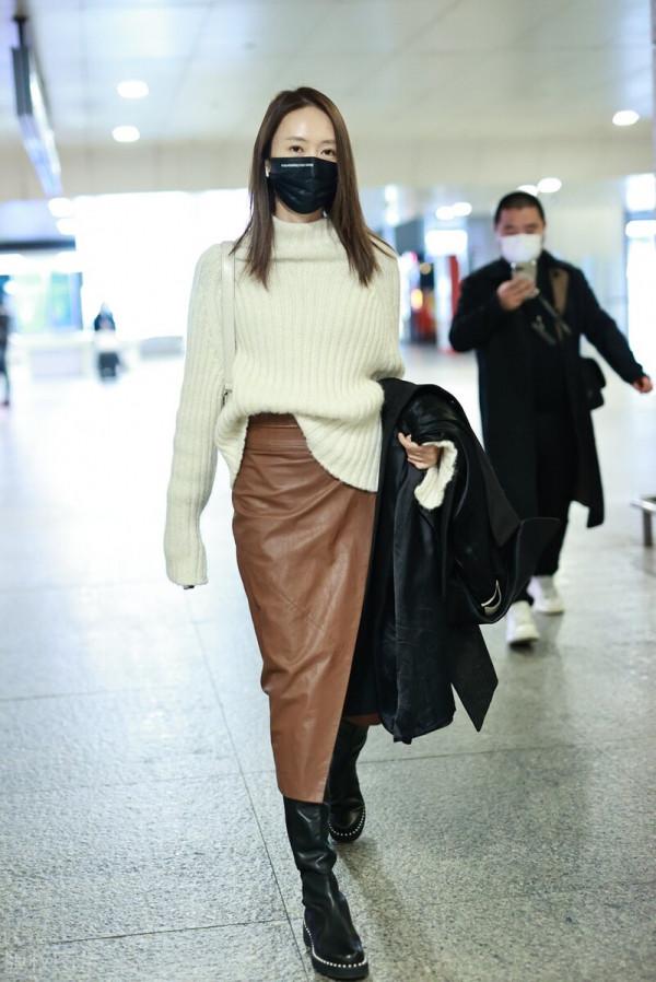童瑤穿白色高領毛衣搭配棕色開衩皮裙，腳踩黑色長靴溫柔優雅
