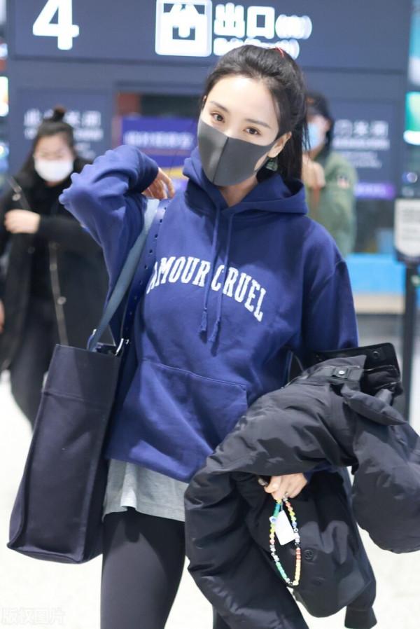 王紫璇穿藍色字母衛衣搭配小黑褲，手拿短款羽絨服溫暖陽光