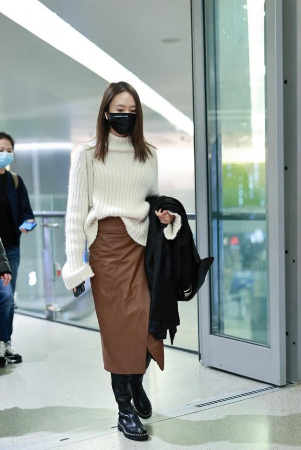 童瑤穿白色高領毛衣搭配棕色開衩皮裙，腳踩黑色長靴溫柔優雅