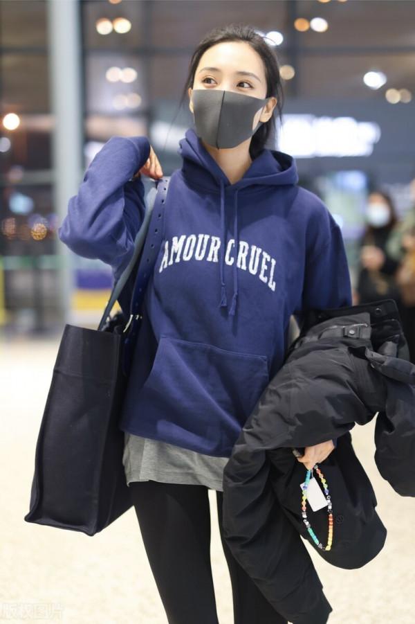 王紫璇穿藍色字母衛衣搭配小黑褲，手拿短款羽絨服溫暖陽光