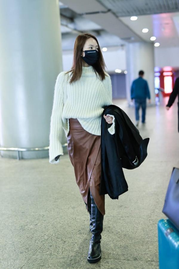 童瑤穿白色高領毛衣搭配棕色開衩皮裙，腳踩黑色長靴溫柔優雅