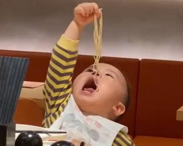 山東一萌娃給自己喂麵條，頭抬得老高半天吃不到，網友：講究人