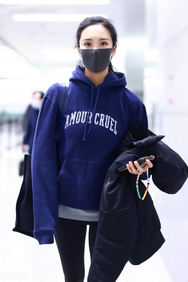 王紫璇穿藍色字母衛衣搭配小黑褲，手拿短款羽絨服溫暖陽光