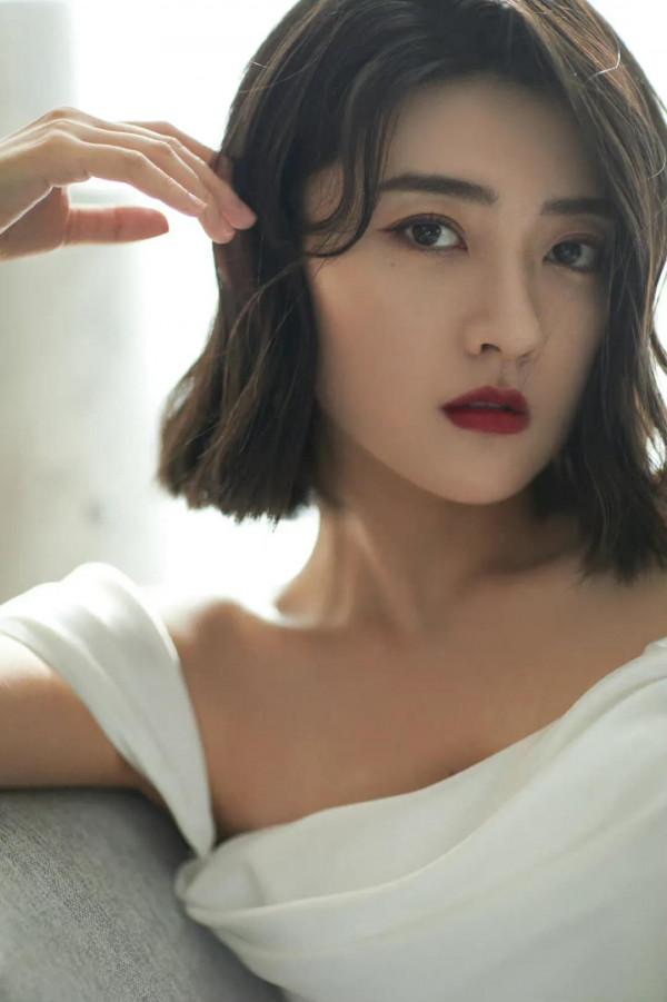 梁潔百褶裙氣質清雅，一頭微卷短髮精緻時髦，隨意撩耳後優雅美麗