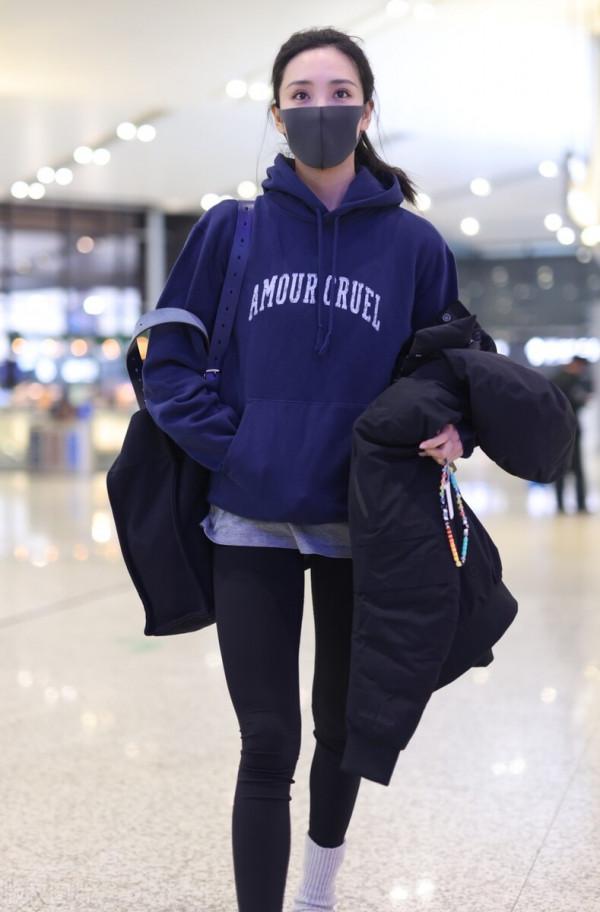 王紫璇穿藍色字母衛衣搭配小黑褲，手拿短款羽絨服溫暖陽光