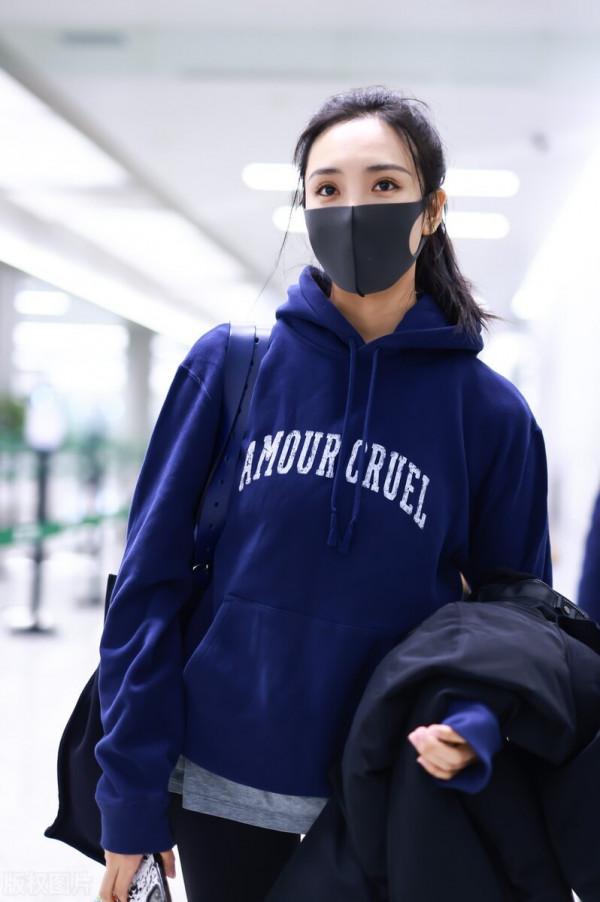 王紫璇穿藍色字母衛衣搭配小黑褲，手拿短款羽絨服溫暖陽光