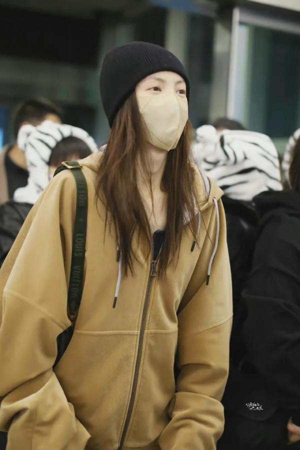 金晨機場私服，棕連帽外套搭配後開衩毛邊牛仔褲，眼睛散發著笑容