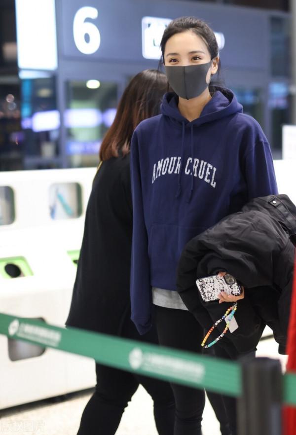 王紫璇穿藍色字母衛衣搭配小黑褲，手拿短款羽絨服溫暖陽光