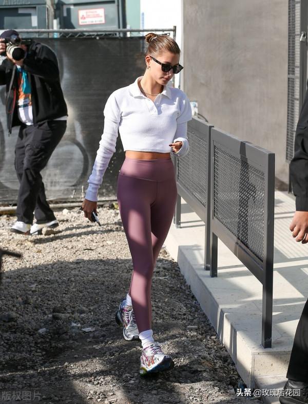 海莉-比伯白色翻領上衣搭紫色瑜伽褲，戴墨鏡盤發隨性大方